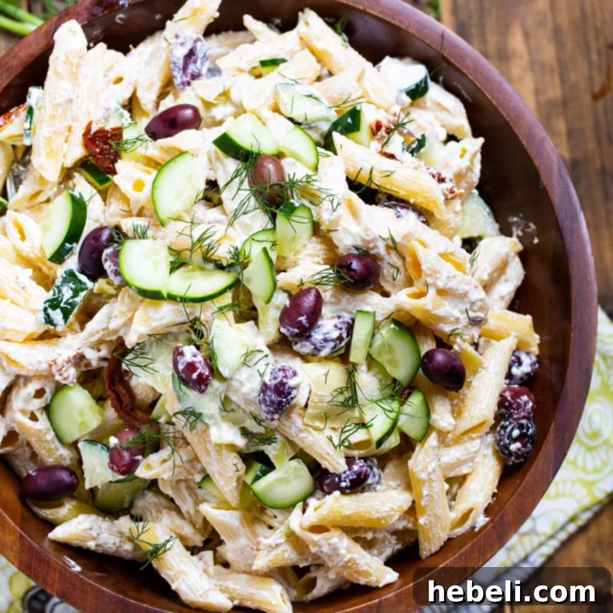 Large wooden bowl filled with vibrant Tzatziki Pasta Salad, showcasing the pasta, olives, and dressing.