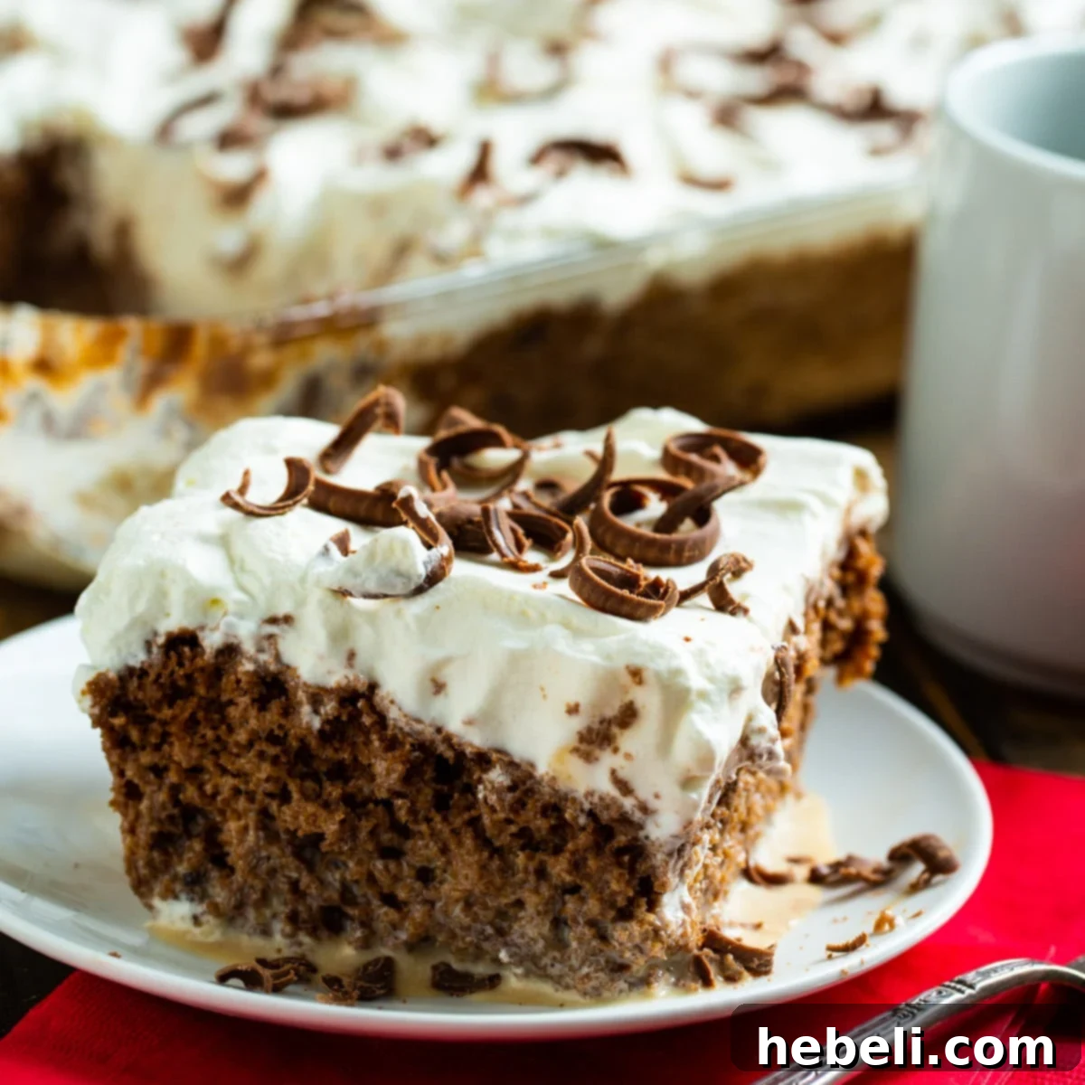 A delectable slice of Coffee Tres Leches Cake, perfectly moist and topped with whipped cream, on a small white plate.