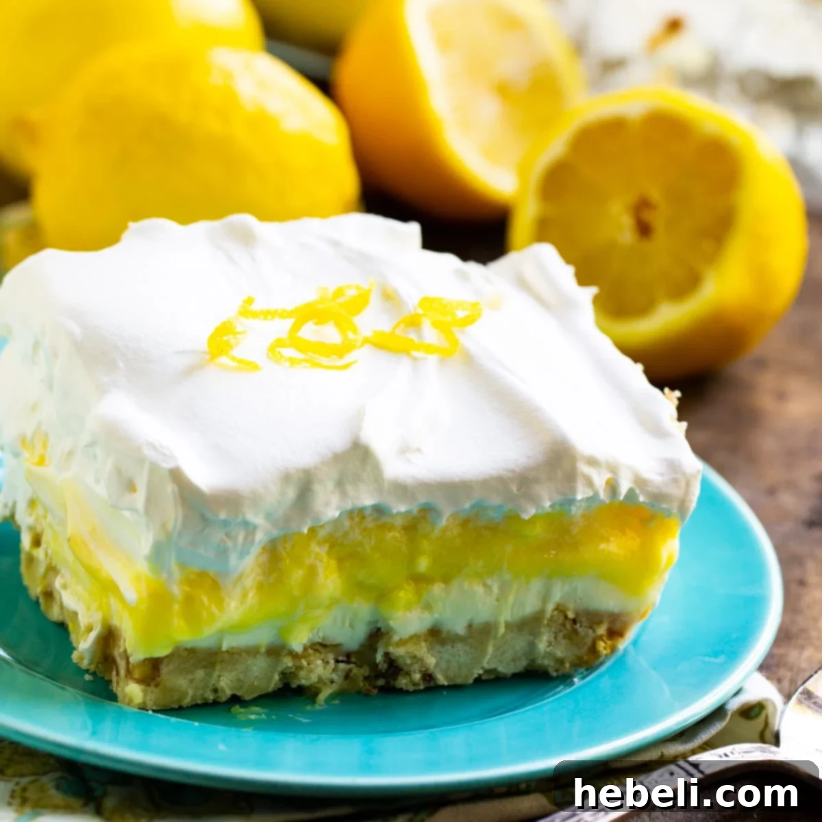 Velvet Lemon Bliss 2 A perfectly sliced piece of Lemon Lush on a blue plate, showcasing its beautiful layers and inviting texture.