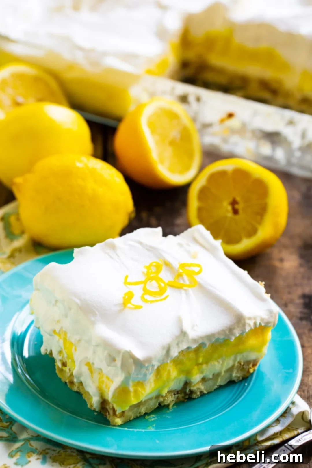 Velvet Lemon Bliss 3 A stunning slice of Lemon Lush on a small white plate, adorned with fresh lemon slices and green mint leaves in the background, highlighting its fresh appeal.