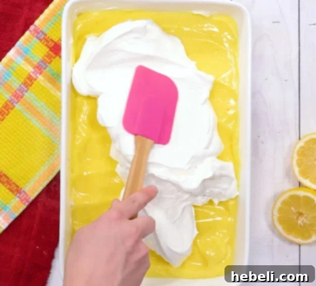 Velvet Lemon Bliss 7 The final step: spreading light and airy whipped topping over the Lemon Lush dessert before chilling.