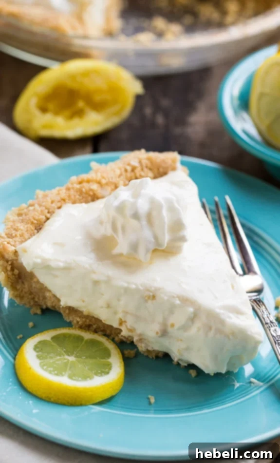 Lemon Icebox Pie slice garnished with fresh raspberries and lemon zest