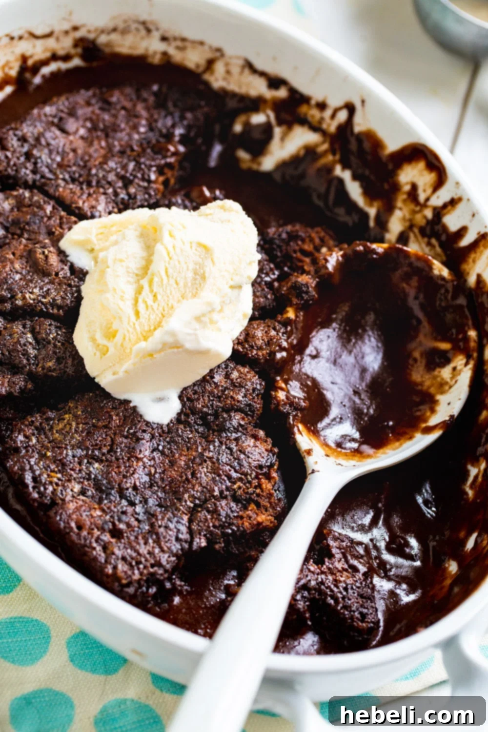 Warm Chocolate Cobbler topped with melting vanilla ice cream in a baking dish.