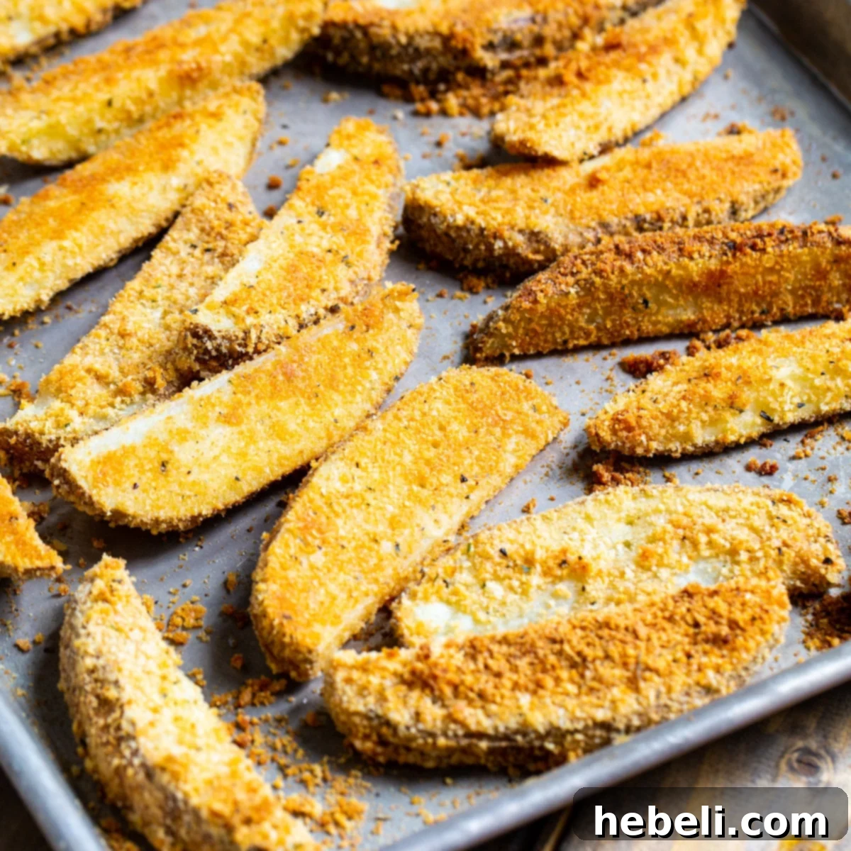 Golden brown Parmesan Crusted Ranch Potato Wedges generously coated with seasoning, arranged on a baking sheet, ready to be served.