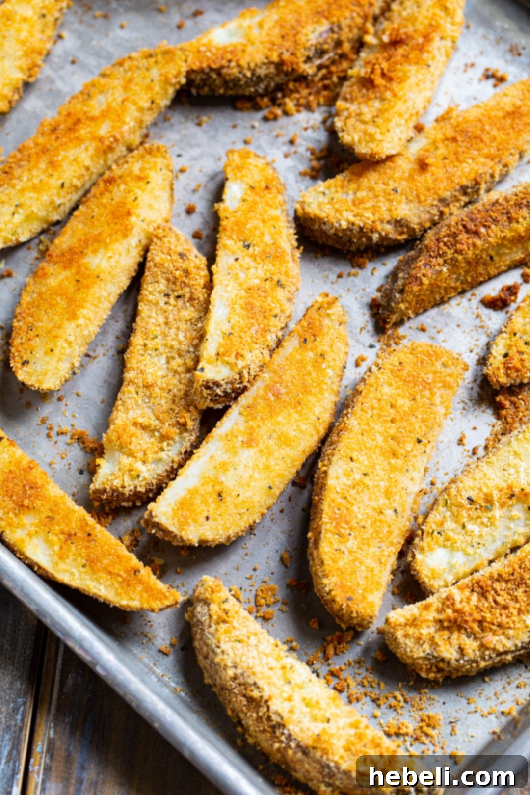Freshly baked potato wedges, perfectly golden and slightly crisped, arranged on a baking sheet straight out of the oven.