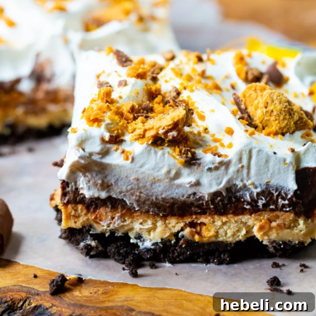 A perfectly sliced piece of Butterfinger Chocolate and Peanut Butter Lush, showcasing its delicious layers, resting on parchment paper.