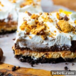 Slice of Butterfinger Chocolate and Peanut Butter Lush on a piece of parchment paper, highlighting the layers.