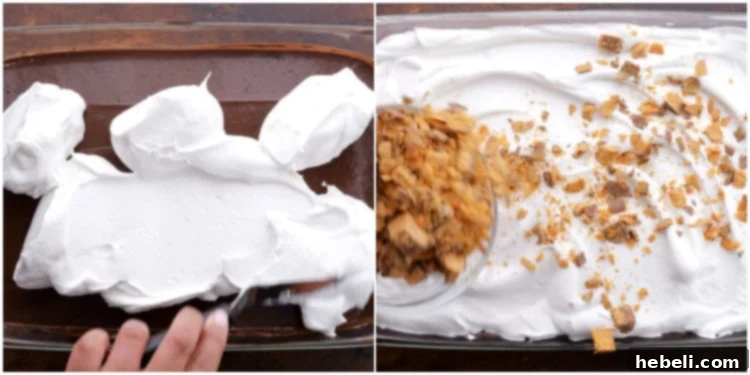 Spreading the final layer of Cool Whip over the chocolate pudding and topping generously with crushed Butterfinger candy for a finishing touch.