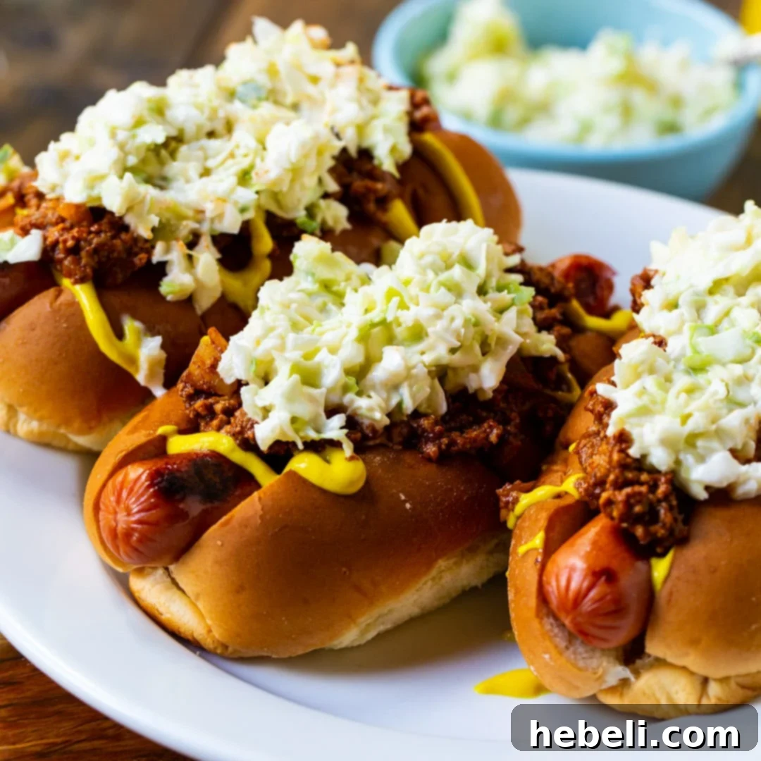 Three Carolina-Style Slaw Dogs on a plate, showcasing the chili, mustard, and coleslaw.