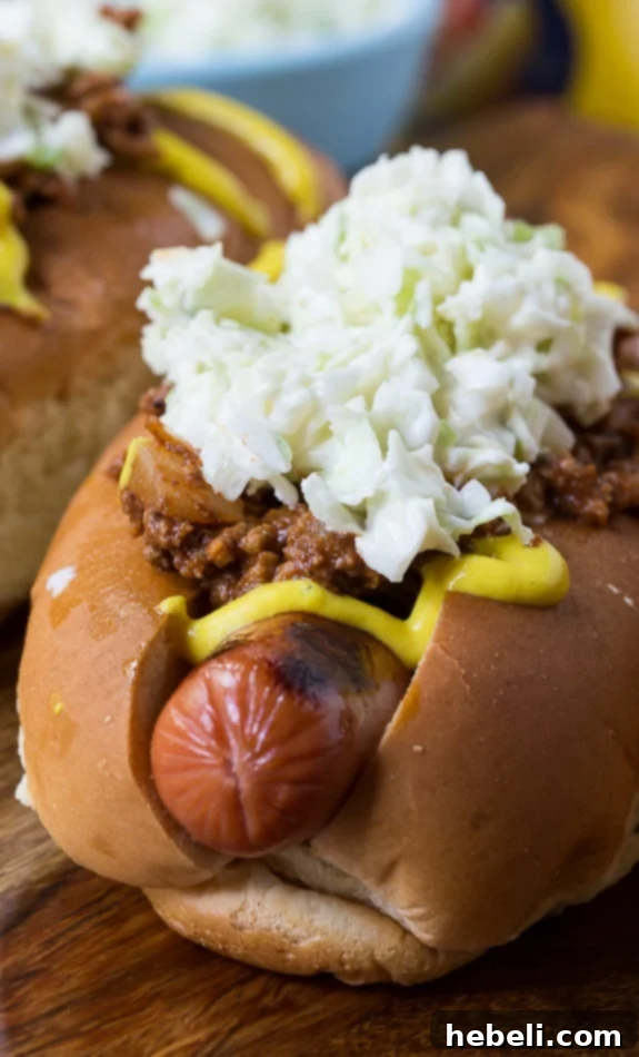 Close-up of a Carolina-Style Slaw Dog generously topped with mustard and homemade chili.