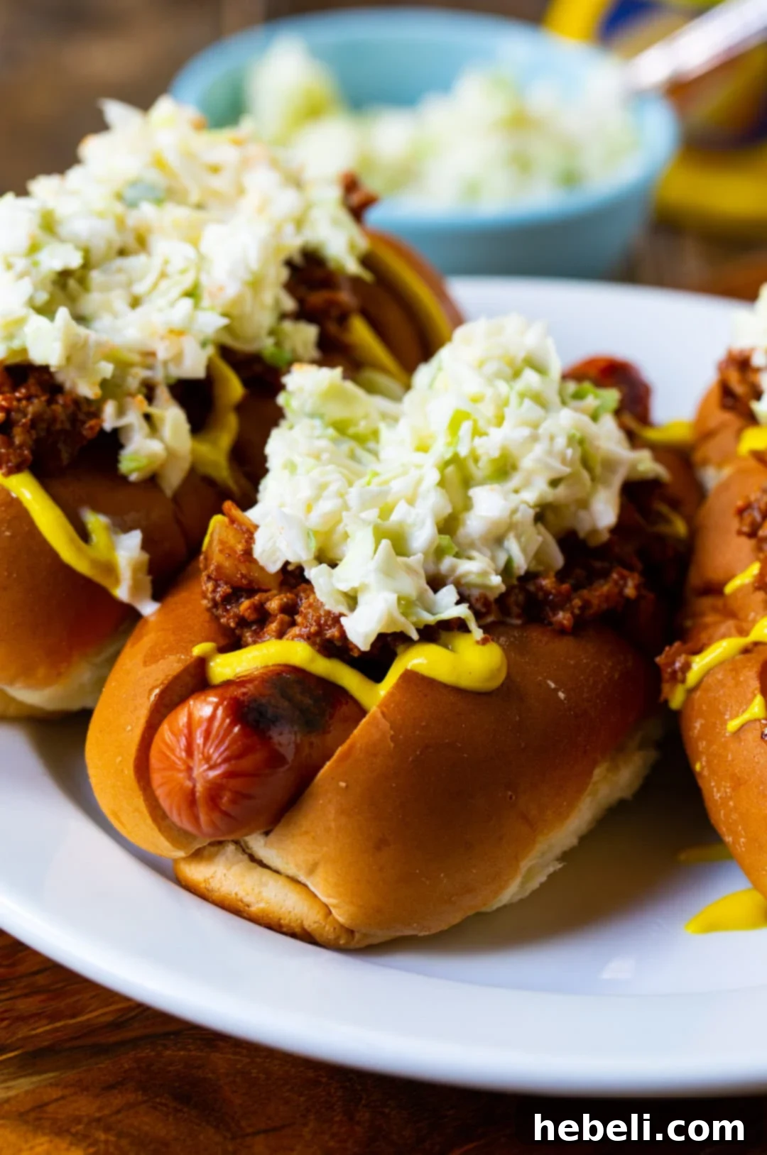 Three Carolina Chili Slaw Dogs neatly arranged on a plate.