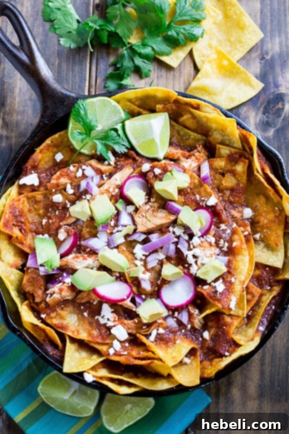 Chicken Chilaquiles prepared with golden tortilla chips, seasoned chicken, a vibrant red chile sauce, and a generous sprinkle of cotija or queso fresco cheese, ready to be served.