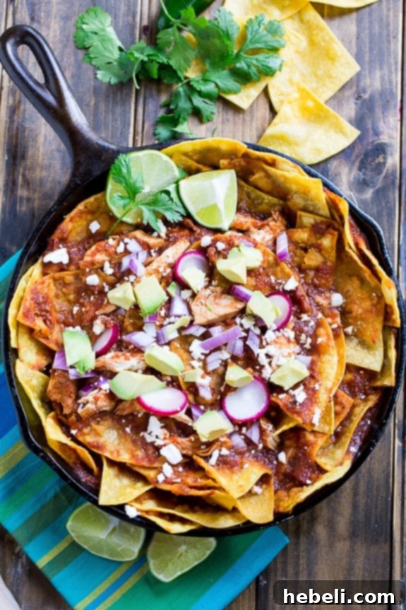 Detailed view of Chicken Chilaquiles featuring crispy corn tortilla chips, tender chicken, rich red chile sauce, and crumbled cotija or queso fresco cheese.