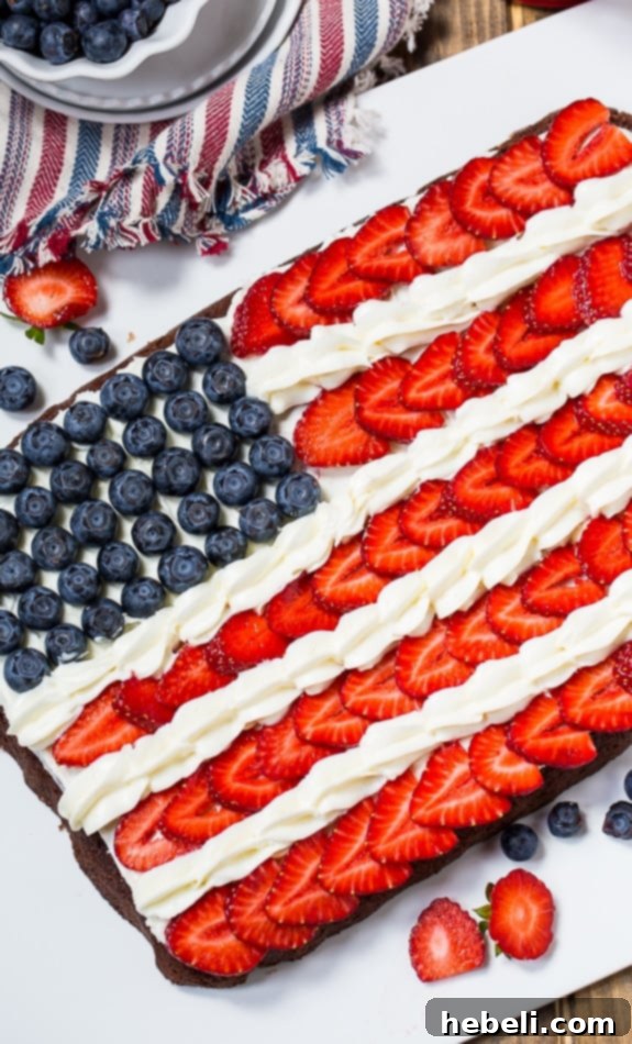 White frosting being spread evenly on cooled Flag Brownies, preparing for fruit decoration.