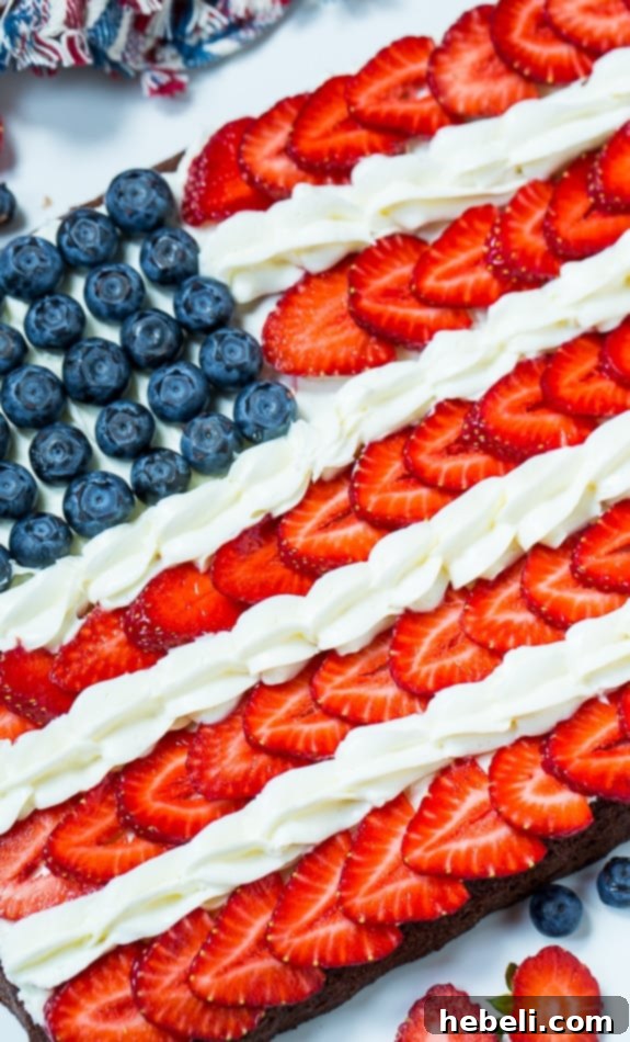Decorated American Flag Brownies with piped white frosting between strawberry rows, ready for celebration.