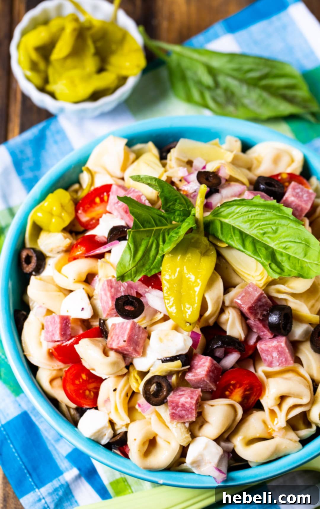 Tortellini Antipasto Pasta Salad served in a clear glass serving bowl, showing layers of ingredients.