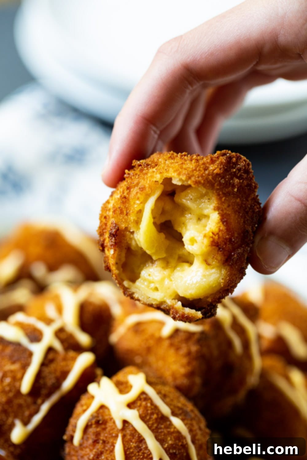 A fried mac and cheese ball with a bite taken out, revealing the soft, creamy macaroni inside its crispy shell.