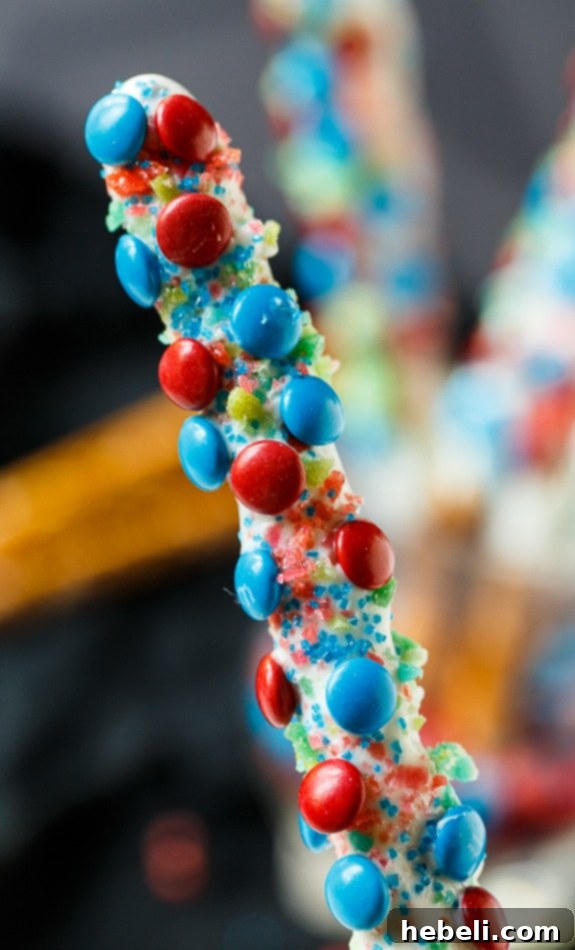 Flavor Burst Pretzel Rods 8 A stunning display of Firecracker Pretzel Rods, adorned with red and blue mini M&Ms and Pop Rocks, ideal for a 4th of July celebration.