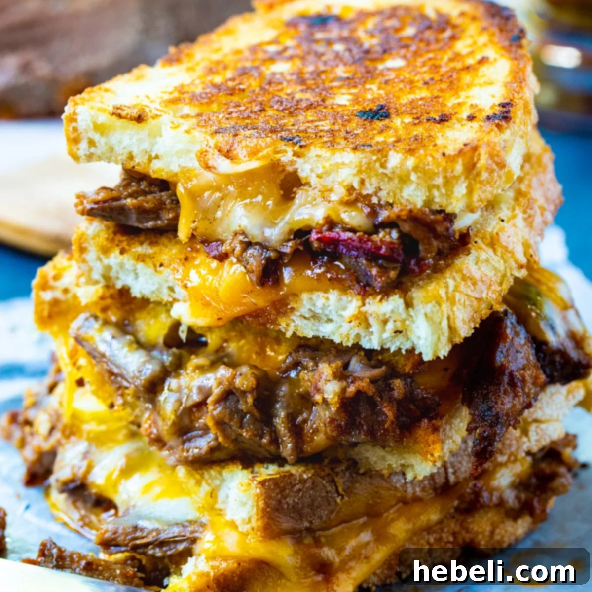 Brisket Grilled Cheese halves stacked on top of each other, showcasing melted cheese and tender brisket.