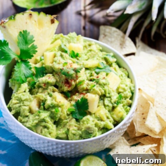 Spicy Pineapple Guacamole - creamy, sweet, and spicy, garnished with fresh cilantro and pineapple chunks, served with tortilla chips
