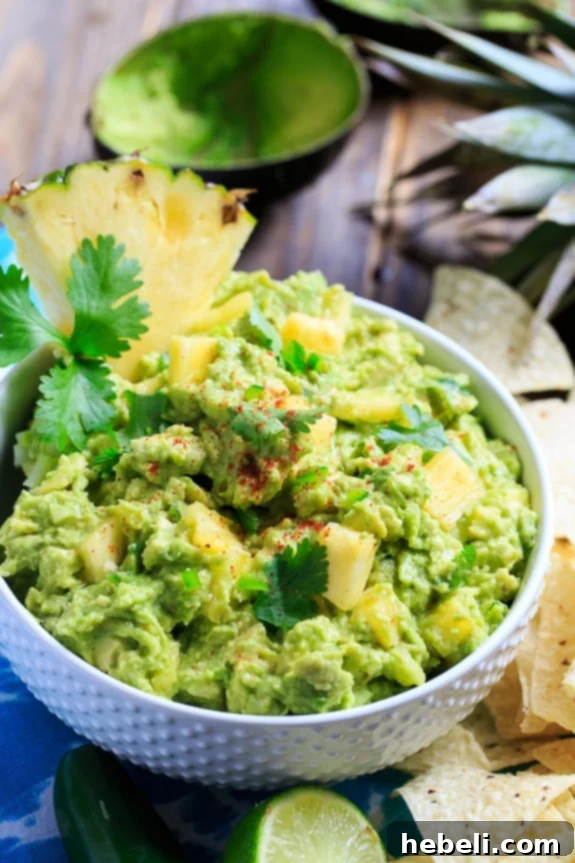 Close-up of fresh Spicy Pineapple Guacamole with tortilla chips and a lime wedge, showcasing the vibrant colors and creamy texture