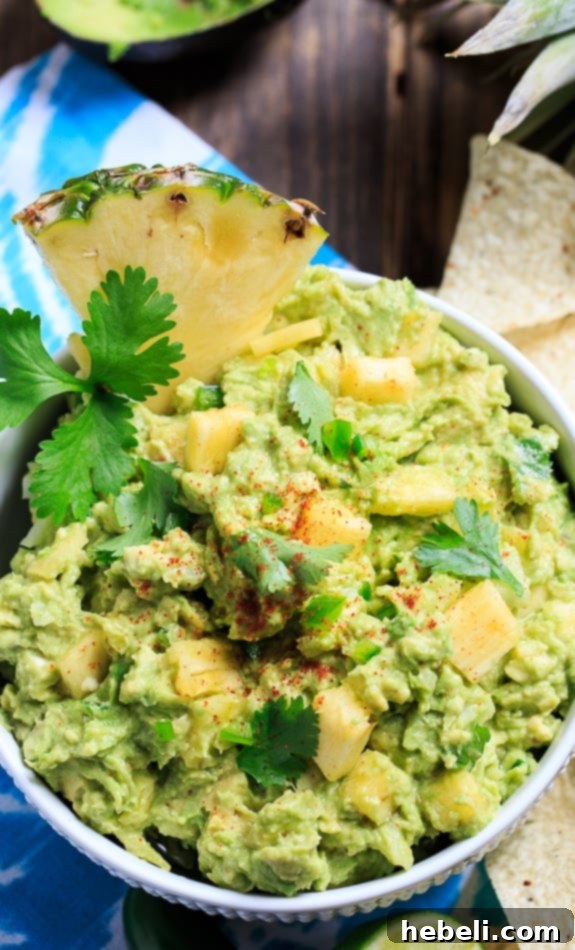 Spicy Pineapple Guacamole in a decorative bowl, ready to serve with a side of crunchy tortilla chips on a wooden board