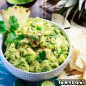 Spicy Pineapple Guacamole with fresh cilantro and lime wedges on a white bowl