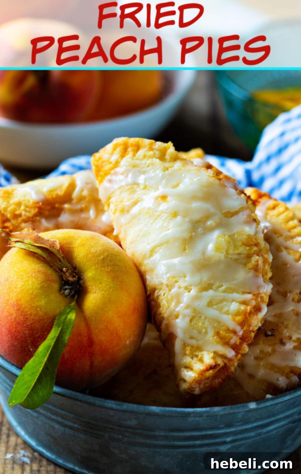 Golden Crispy Peach Turnovers 5 A collection of freshly fried peach pies, drizzled with a sweet glaze, sitting invitingly in a metal tin, with a focus on their golden-brown color and irresistible texture. Made with fresh summer peaches.