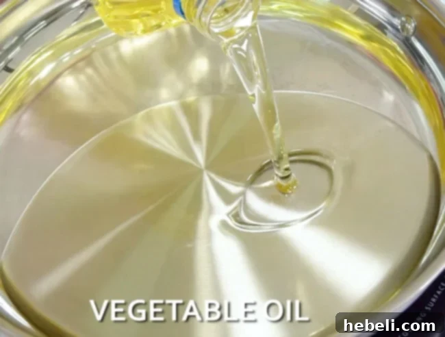 Vegetable oil being poured into a hot skillet, preparing for frying Southern Fried Pork Chops.