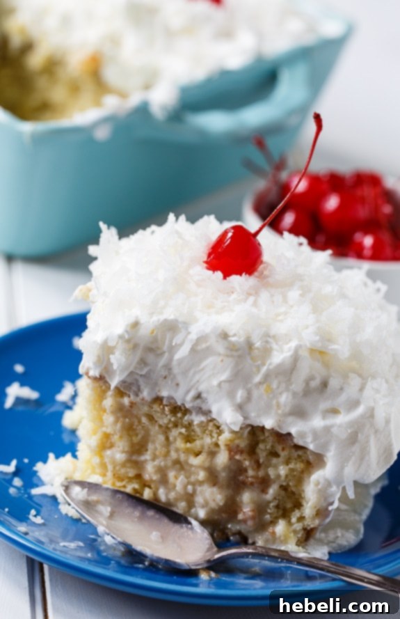 Close-up shot of a slice of Pina Colada Poke Cake showing the moist interior and layers of pineapple and creamy topping, perfect for any summer party.