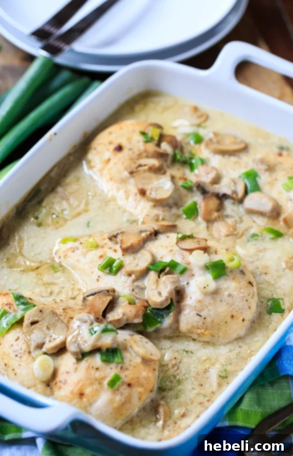Smothered Chicken Breasts baking in a simple mushroom cream sauce in a glass dish, showing the delicious golden-brown crust.