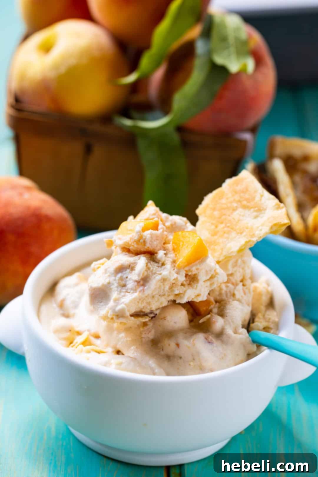 A scoop of homemade Peach Cobbler Ice Cream in a bowl with a spoon, showing its creamy texture and peach flecks.