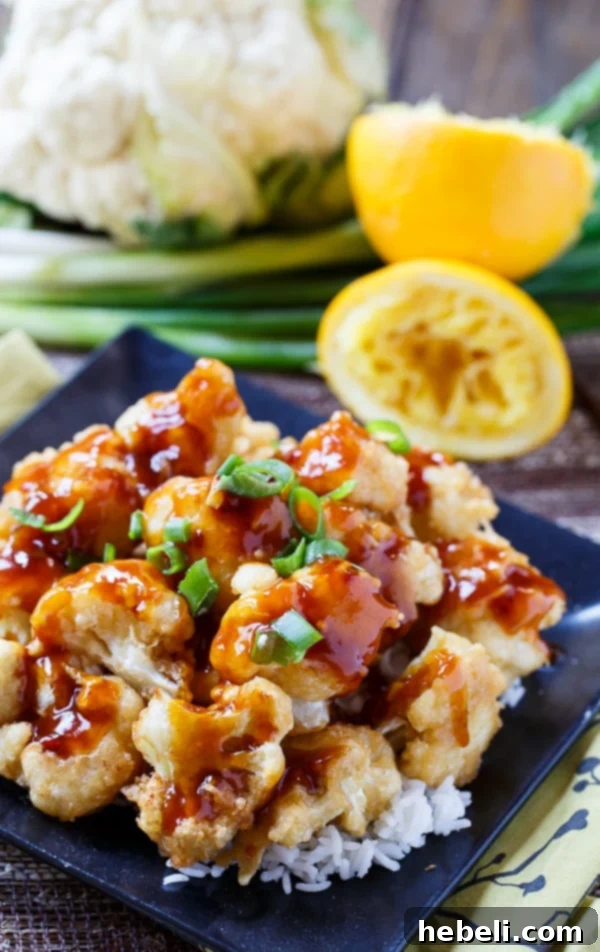 Close-up shot of crispy Orange Cauliflower florets coated in sticky sauce, ready to be served.
