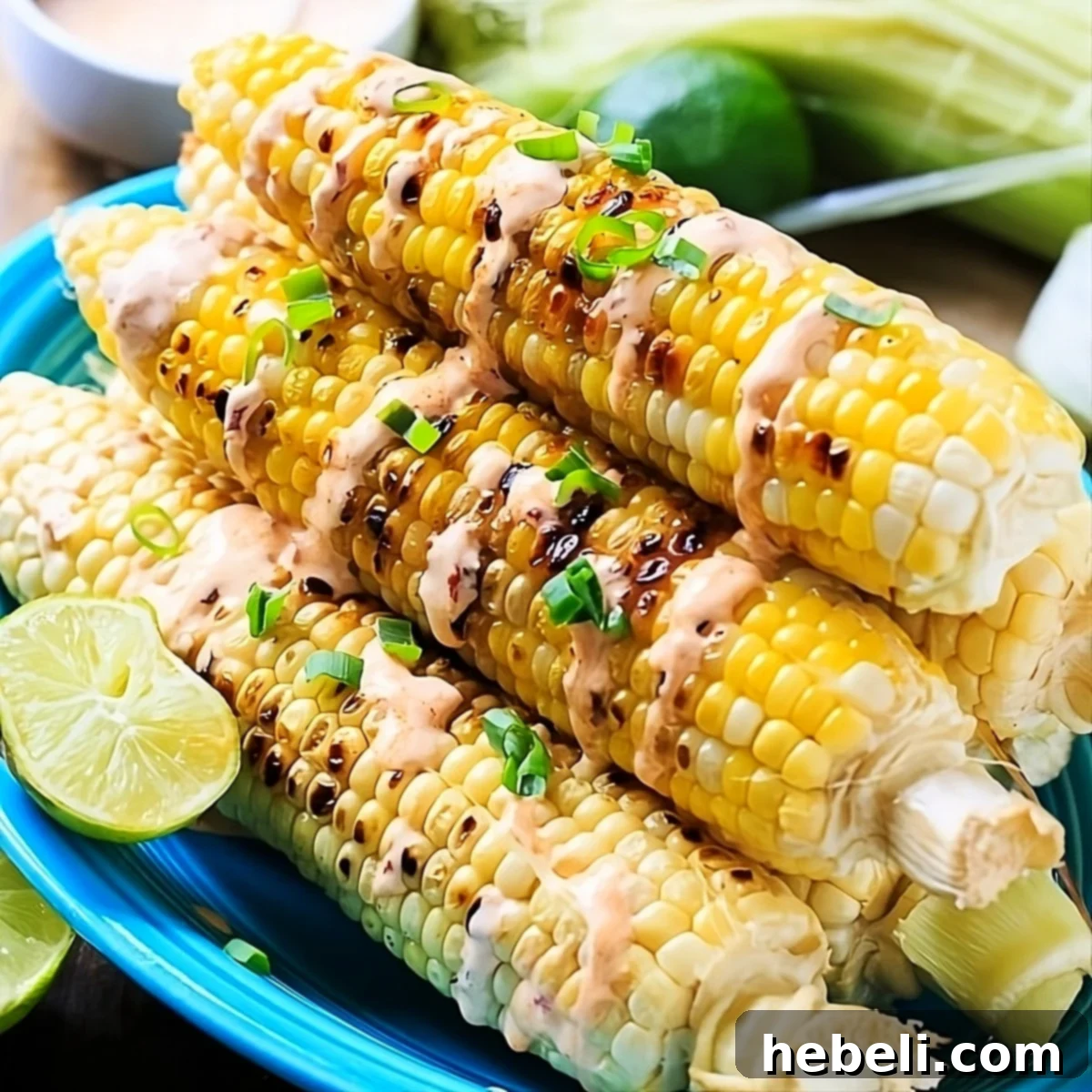 Smoky Grilled Corn with Creamy Chipotle 2 Perfectly grilled corn cobs on a serving platter, drizzled generously with creamy chipotle sauce and garnished with fresh cilantro.