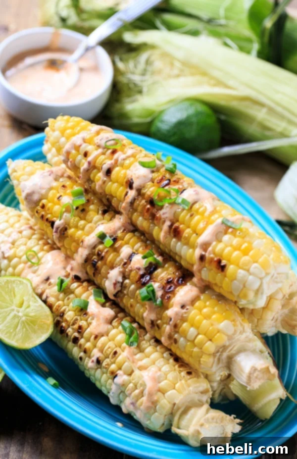 Smoky Grilled Corn with Creamy Chipotle 4 Hands applying olive oil to fresh corn cobs before grilling, emphasizing preparation for perfect charring.