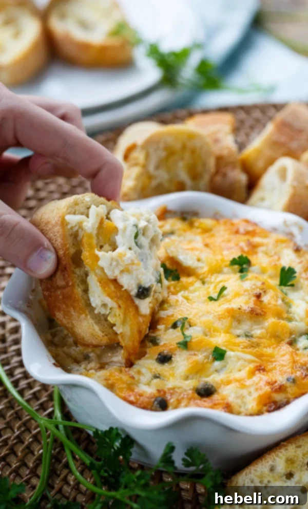 Incredible Hot Crab Dip made with cream cheese, mayonnaise, succulent crab meat, spicy horseradish, briny capers, and sharp cheddar cheese, displayed beautifully.