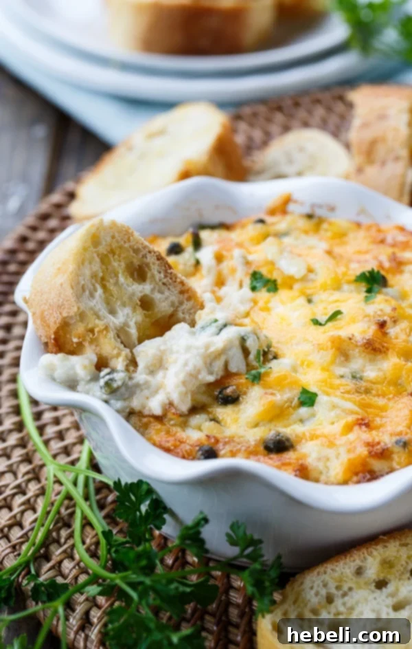 Hot Crab Dip served in a casserole dish with various dippers like crackers, baguette, and celery sticks, highlighting its creamy texture and inviting appearance.