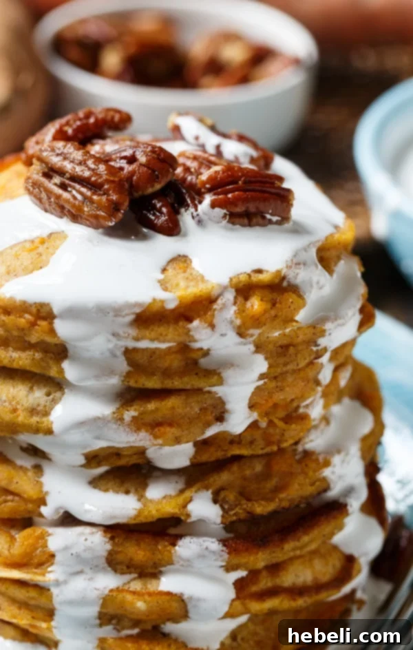 A towering stack of Sweet Potato Pancakes, generously topped with marshmallow syrup and candied pecans.