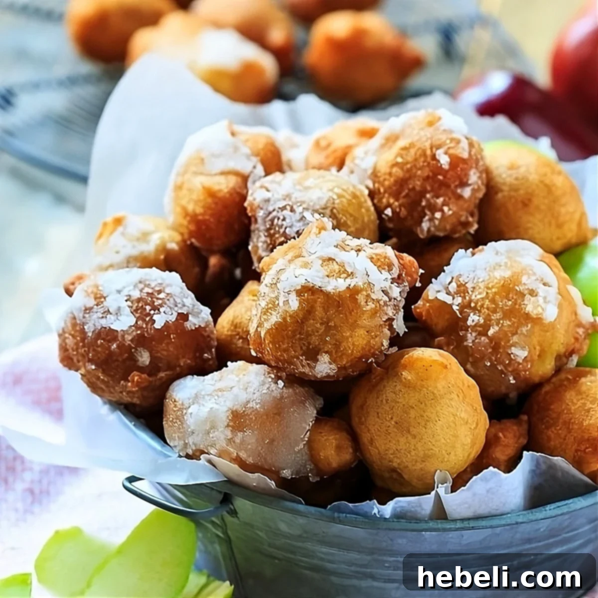 Spiced Apple Delight Puffs 2 Golden-brown apple fritters generously coated in a shimmering bourbon glaze, resting in a rustic metal container, ready to be enjoyed as a perfect fall treat.