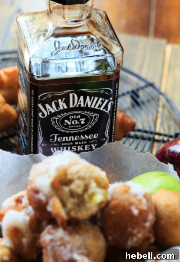 Spiced Apple Delight Puffs 5 An appetizing spread of Bourbon-Glazed Apple Fritters, some with a bottle of Jack Daniel's, emphasizing their artisanal preparation and the adult nature of the treat.