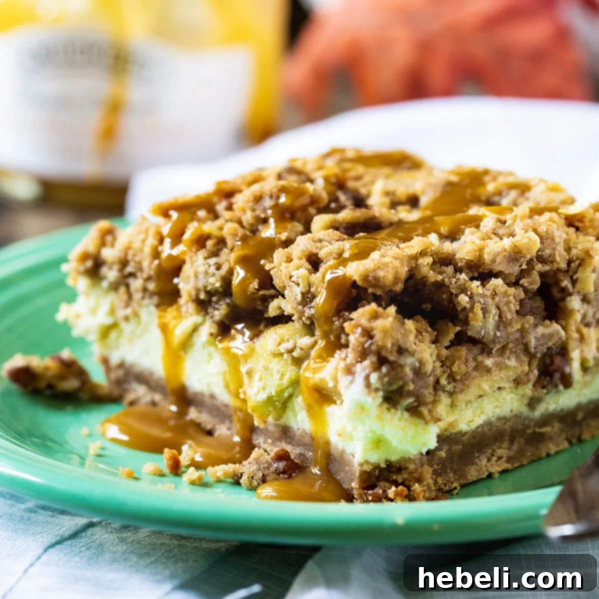 A perfectly portioned Caramel Apple Cheesecake Bar resting on a pristine white plate, showcasing its distinct layers of crust, apple cheesecake, and streusel.