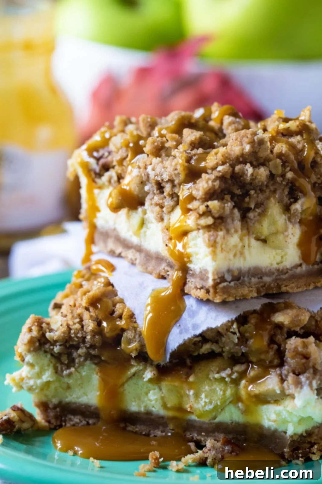 Several Caramel Apple Cheesecake Bars neatly stacked on top of each other, displaying the rich layers of crust, apple cheesecake, and streusel, with a hint of caramel drizzle.