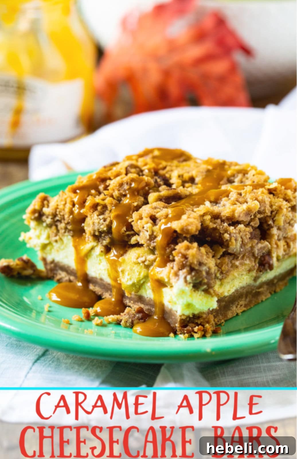 A vibrant and artfully arranged display of Caramel Apple Cheesecake Bars, richly topped with streusel and generous caramel drizzle, set against a backdrop of fresh, crisp red and green apples.