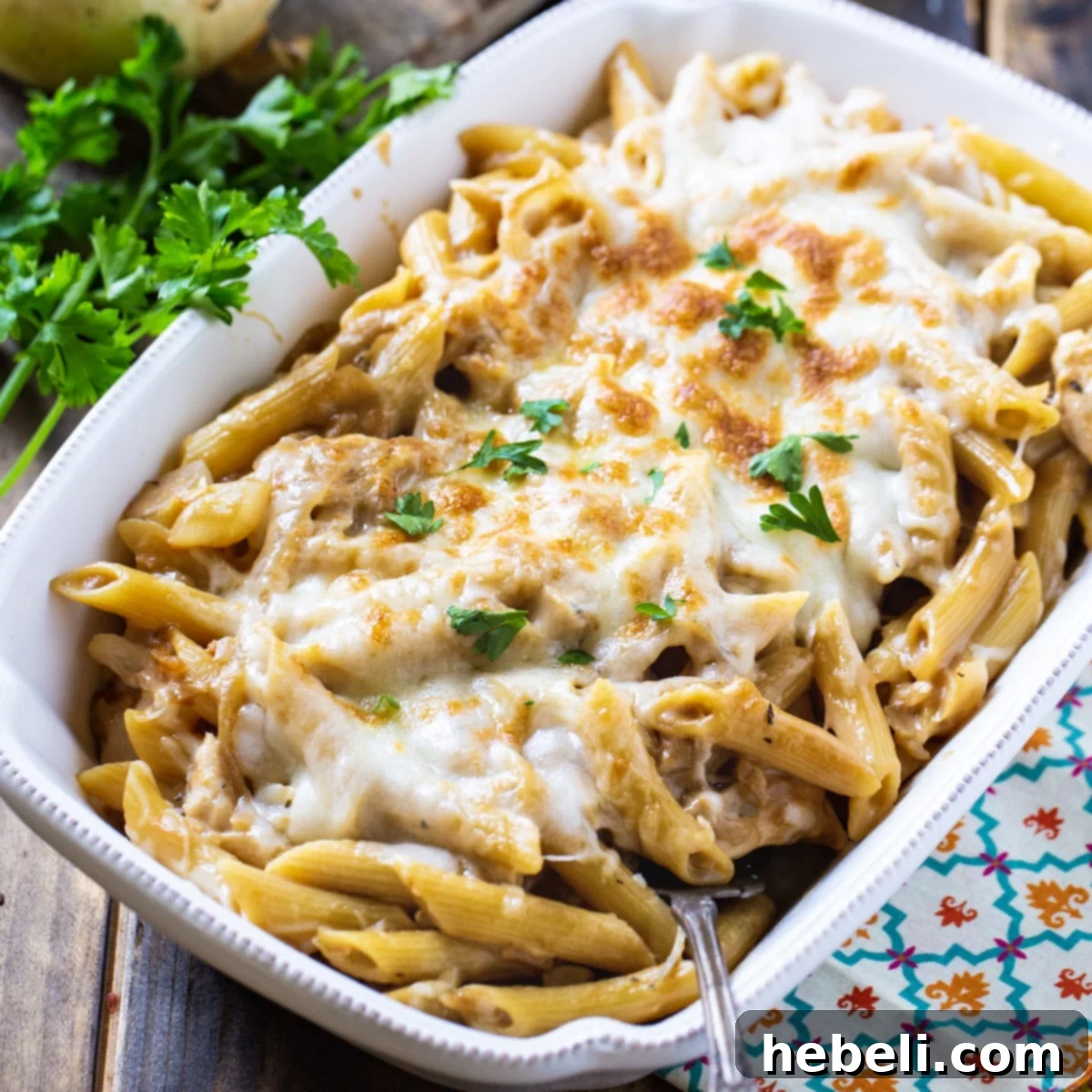 A bubbling casserole dish filled with French Onion Pasta, topped with golden-brown melted cheese and caramelized onions.