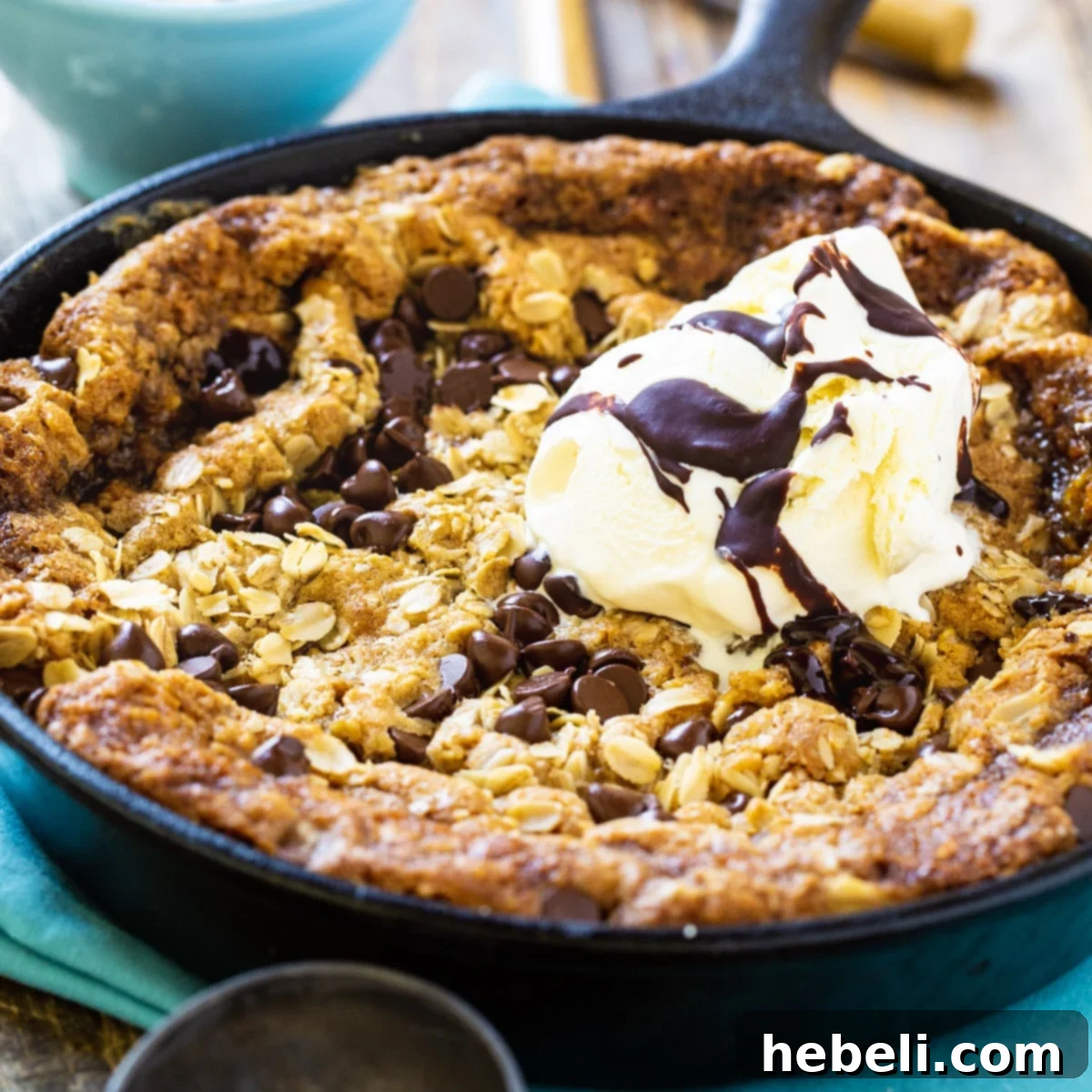 Chocolate Chip-Peanut Butter Oatmeal Skillet Cookie in a cast iron pan, ready to be served warm with ice cream.