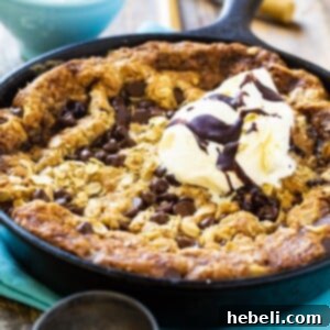 Close-up of a skillet cookie with melting chocolate chips and a rich, golden-brown crust.