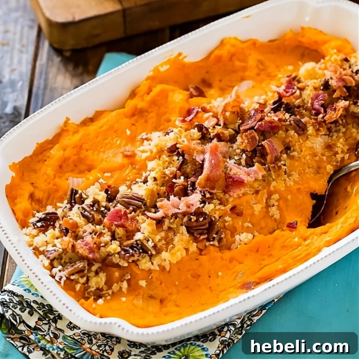 A golden-brown Savory Sweet Potato Casserole in a baking dish, garnished with fresh herbs and crispy bacon.