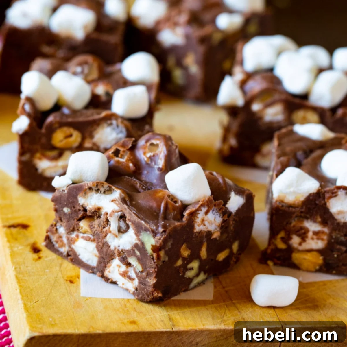 Perfectly cut squares of Rocky Road Fudge on a rustic cutting board, showcasing almonds and marshmallows.