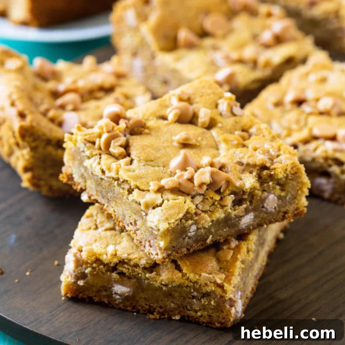 Delicious Butterscotch Toffee Blondies arranged on a rustic wood cutting board, showcasing their chewy texture and generous topping of chips and bits.