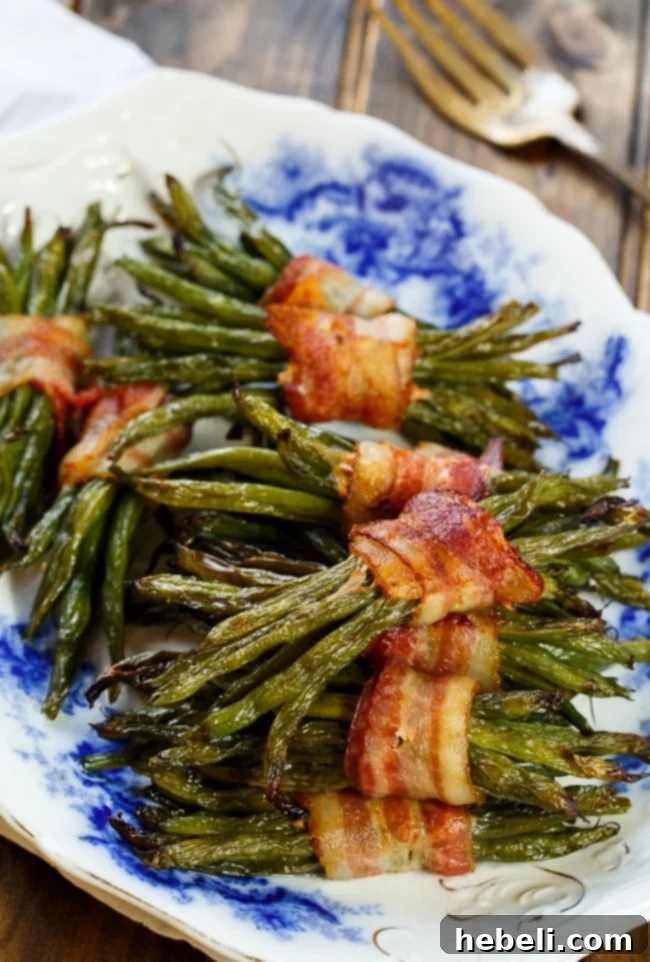 Close-up of crispy Bacon Wrapped Green Bean Bundles on a baking sheet.